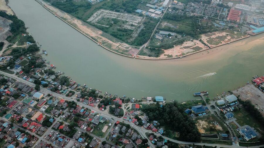 Aerial view of a long river running along a small settlement with residential houses