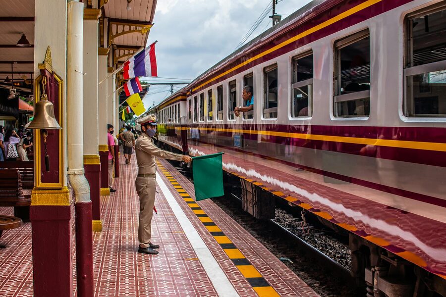 A conductor directs a Thai train at Ayutthaya railway station
