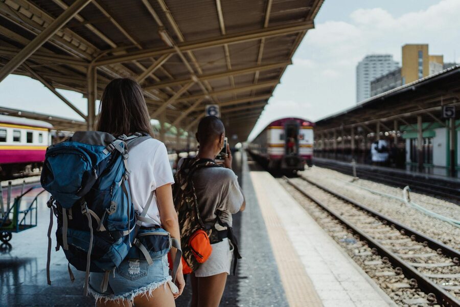 Two backpackers waiting at a railway platform, ready for their travel adventure