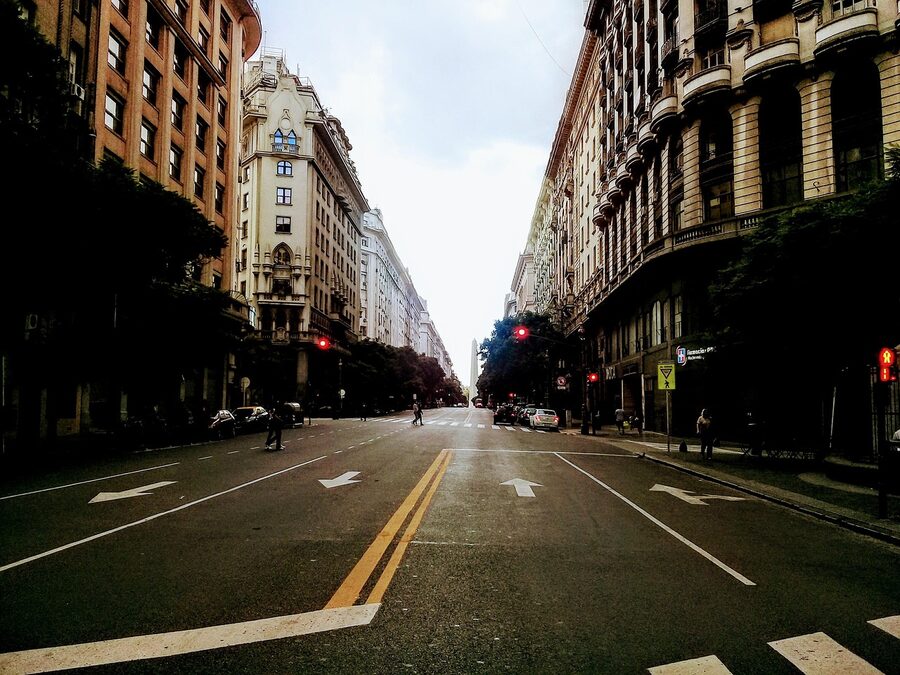 A busy Buenos Aires street with traffic and traveler-bound buses