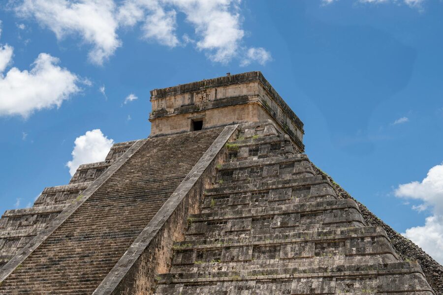 The stepped pyramid of Chichen Itza against a bright blue sky