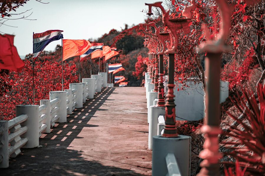 Colourful flags line a scenic pathway in Tha Thewawong, Thailand, on a sunny day