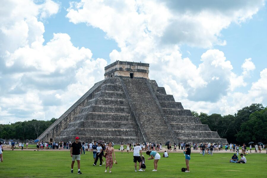 El Castillo pyramid in Chichen Itza with tourists on a sunny day
