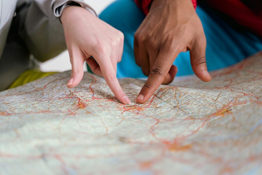 A close-up of diverse hands pointing at a paper map, symbolising travel planning