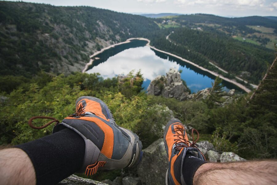 A hikers boots looking out over a lake and forested hills