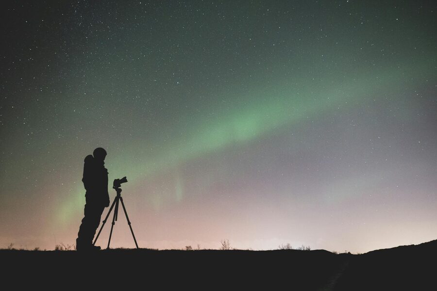 Silhouette of a photographer capturing the Northern Lights in Iceland