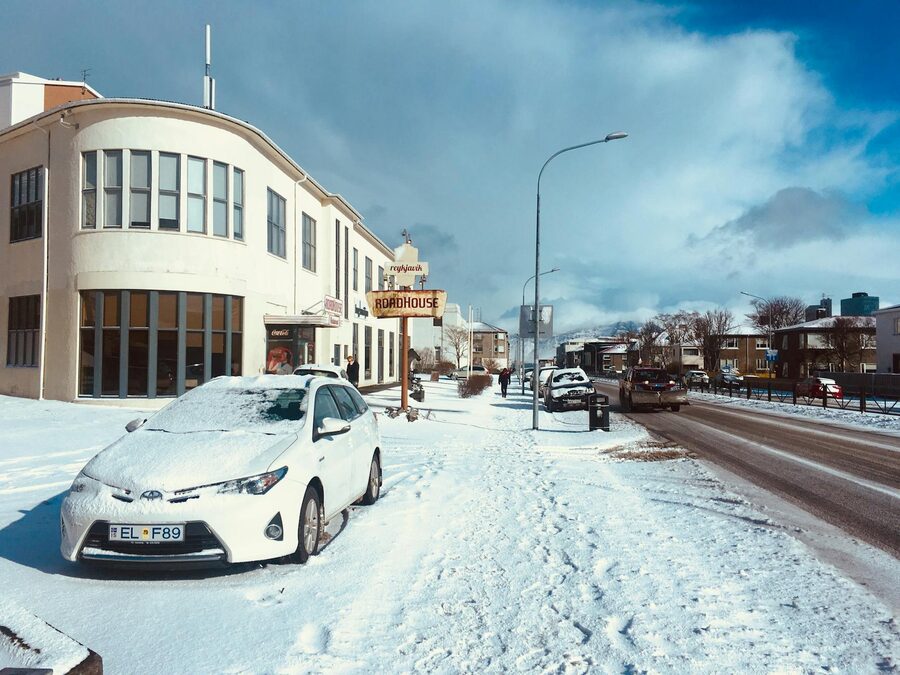 A snowy urban street in Reykjavik in winter, with a car and buildings under a clear sky