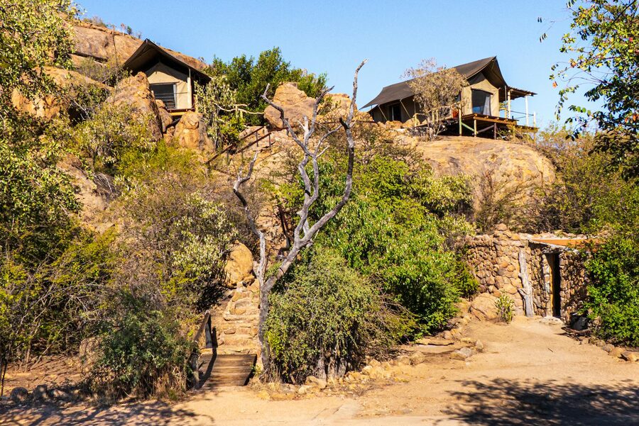 Rustic safari lodges surrounded by rocky landscape and desert vegetation
