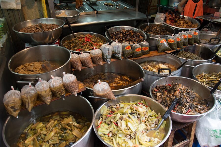 A spread of Thai food and fresh vegetables at an Asian market
